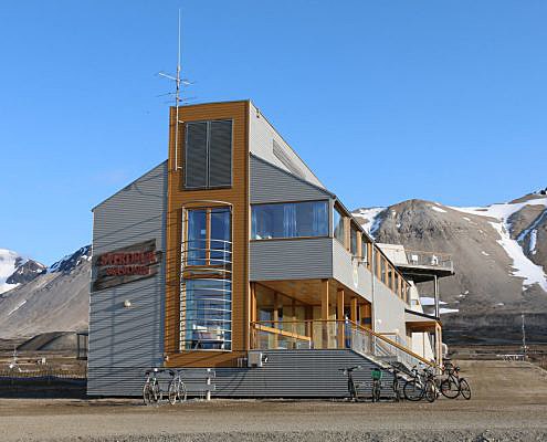 Bygning med snøkledde fjell i bakgrunnen