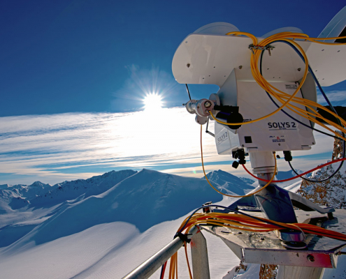 måleinstrument med sol og snedekte fjell i bakgrunn