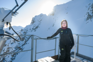 Portrett av kvinne på perrong med snedekte fjell i bakgrunnen