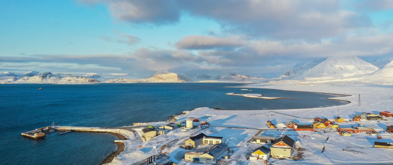 Drone image over coastal line covered by snow, many buildings scattered around