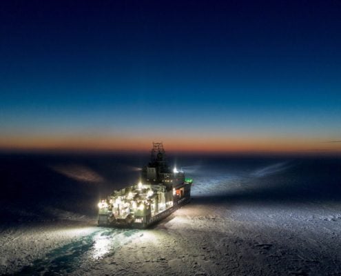 stort fartøy i natt kjører gjennom islagt farvann