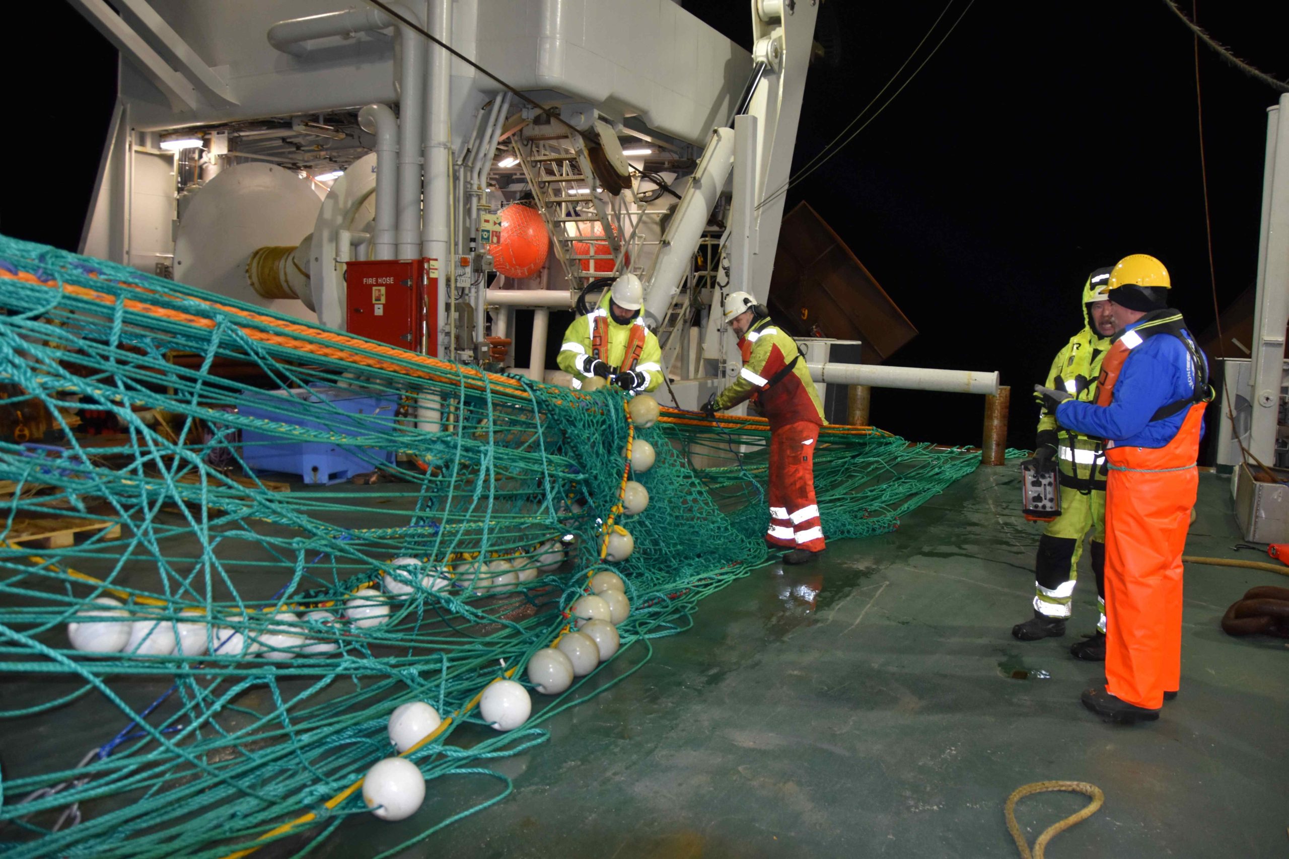 fire personer ved et fiskenett på en tråler