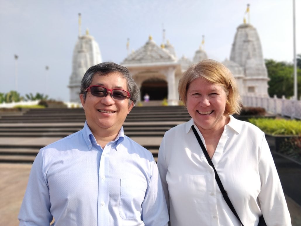 Two persons looking into the camera, with a tempel in the background