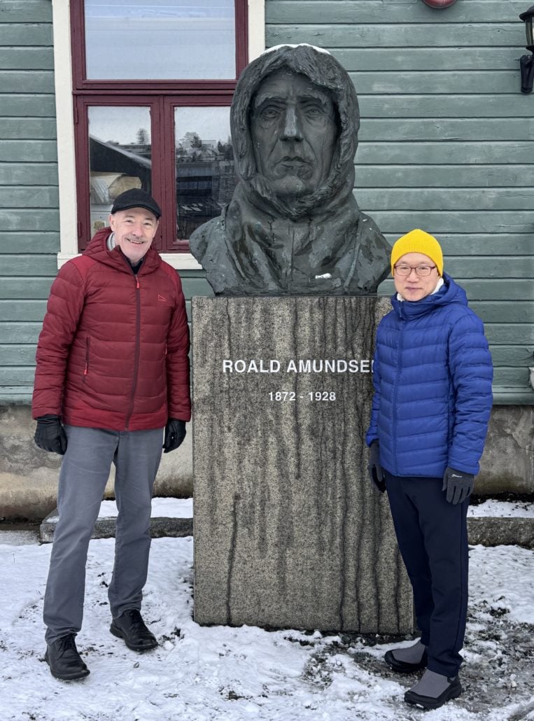To personer står ved en statue av Roald Amundsen