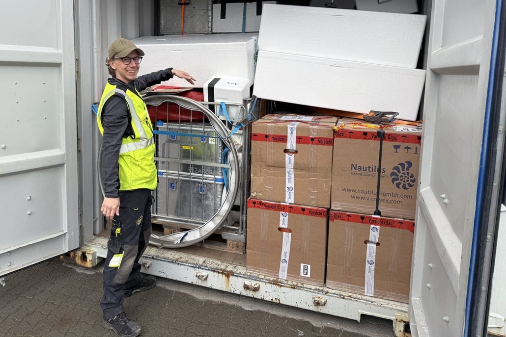 Mann står foran en container full av ting.