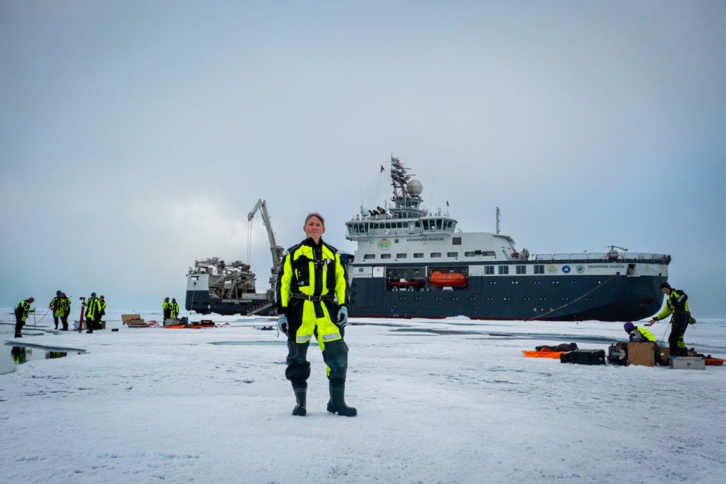 Mann stå i isen foran et forskningsskip
