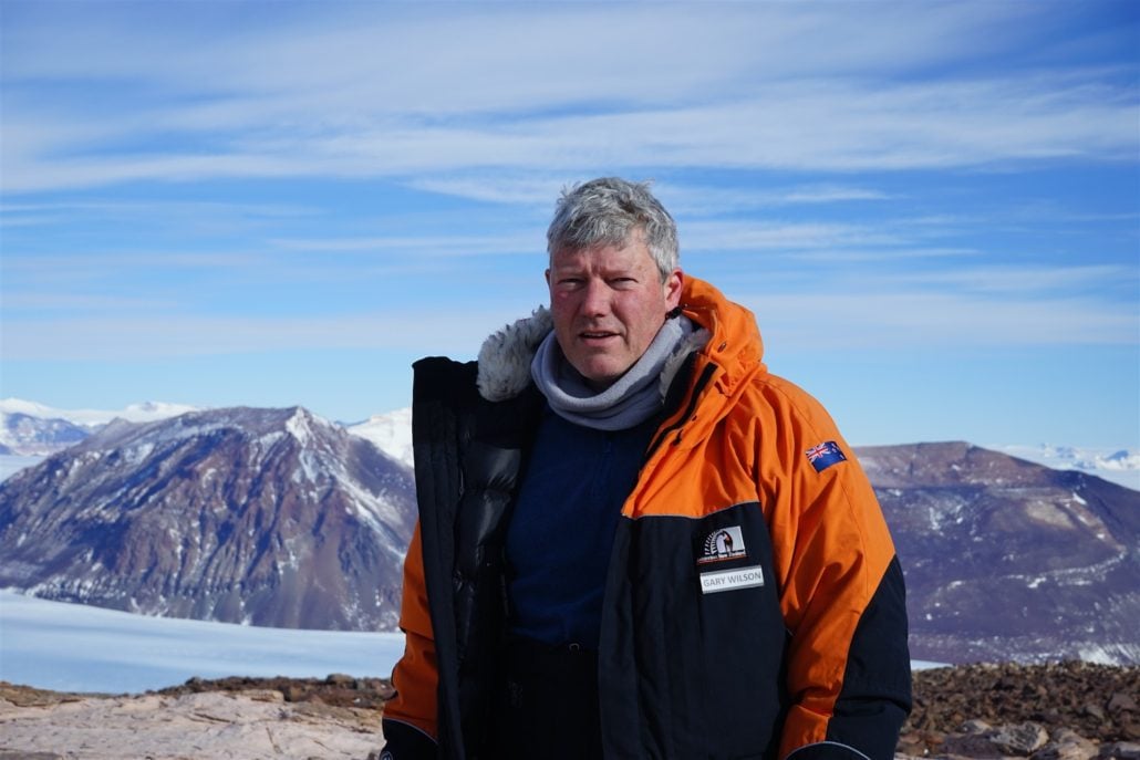 Mann i oransje jakke foran fjell