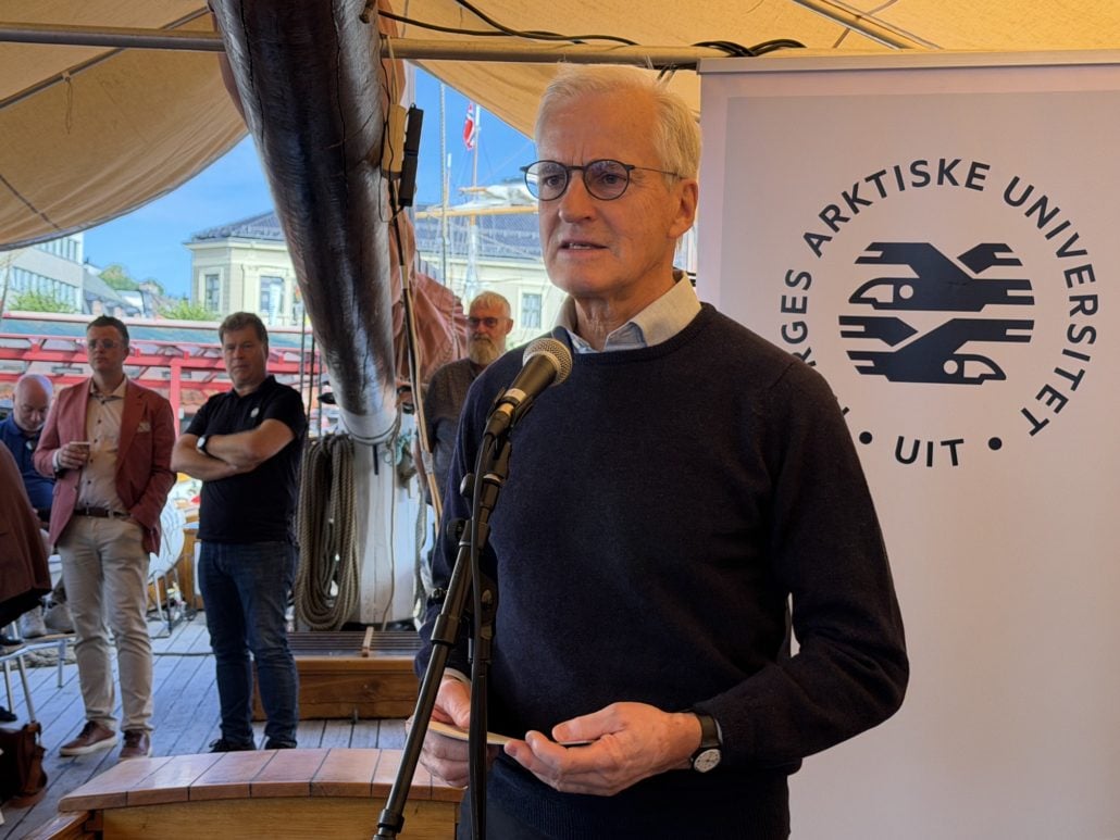 Mann står og snakker i en mikrofon