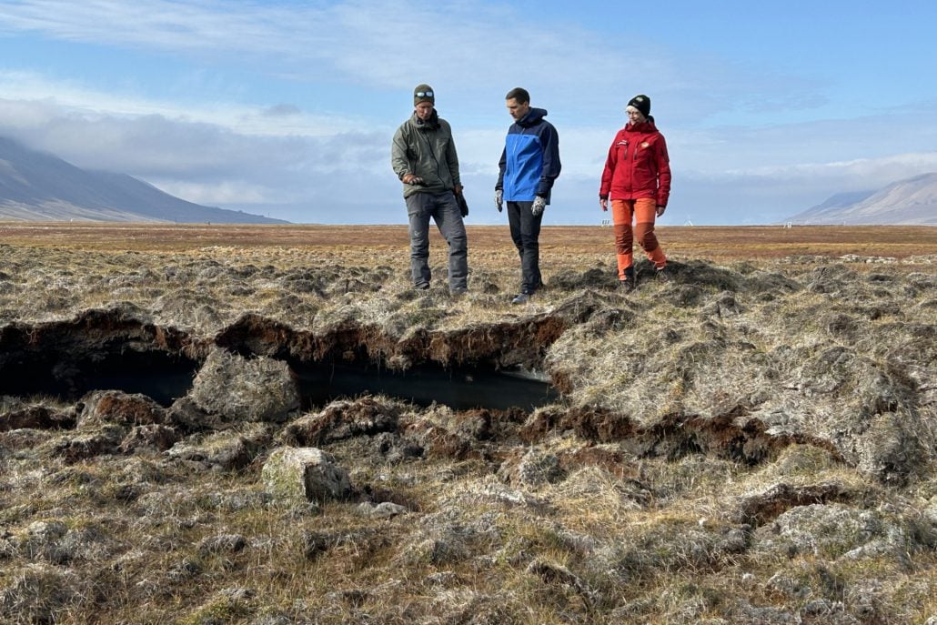 Tre personer står på tundraen på Svalbard.